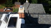 View looking down on the roof, showing shadow of Dave in the lift, the 3rd-floor skylight, the chimney, and the patio far below.