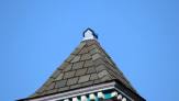 Small sheet-metal cap on top of the peak of the roof, with the blue sky behind.