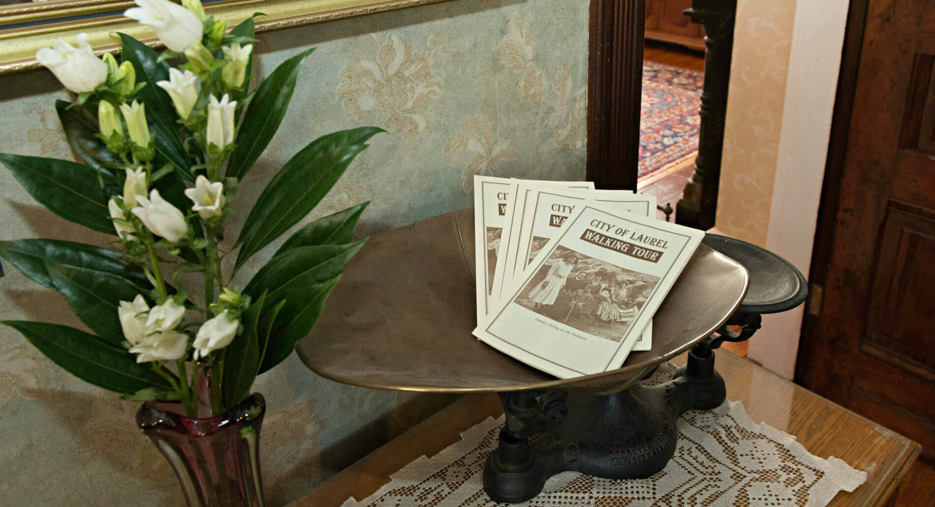 Wooden table against a wall with decorative green plants and white flowers