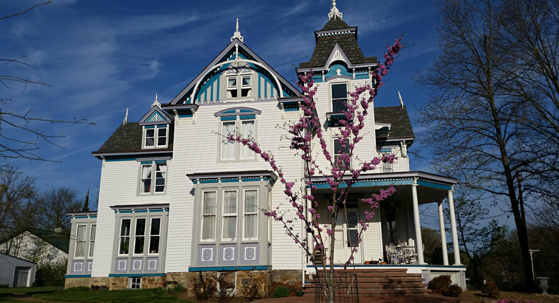 Large white Victorian styled house with blue and grey detailing and black shingles