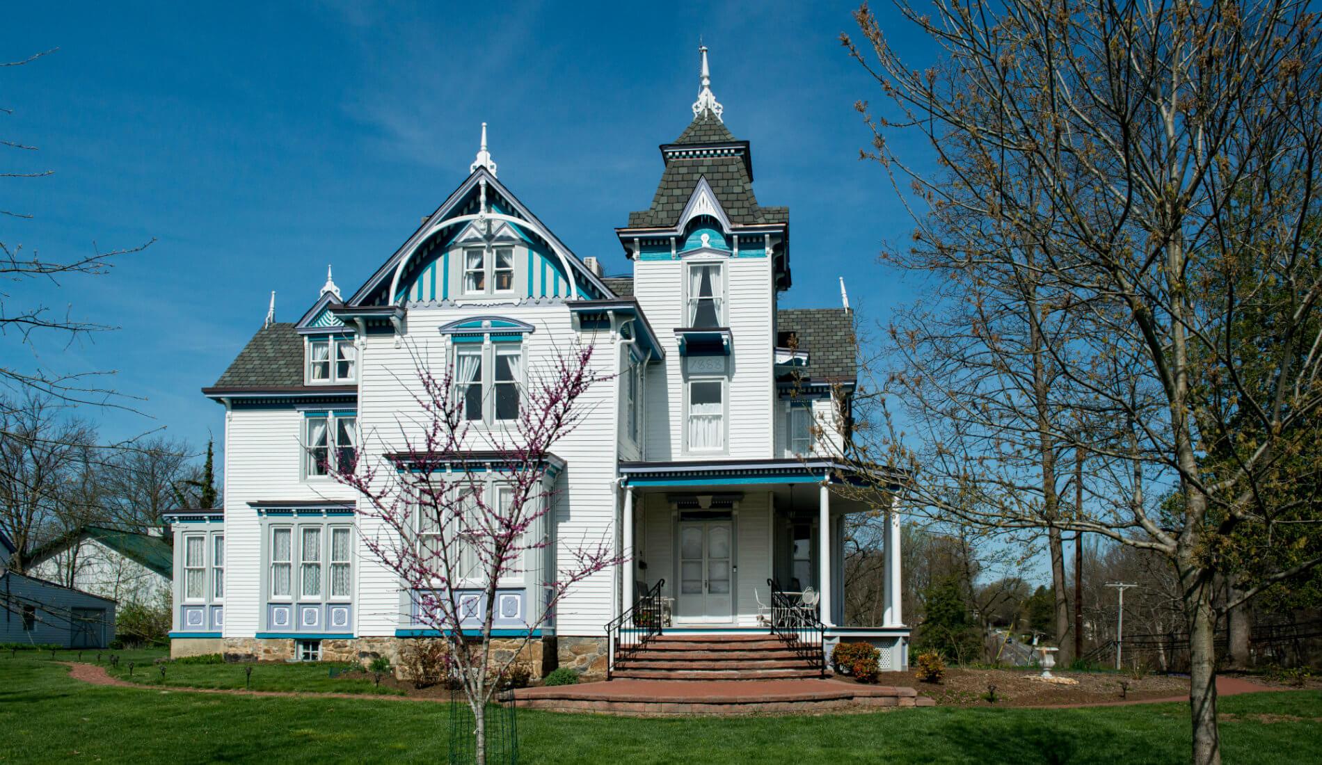 Large white Victorian styled house with blue and grey detailing and black shingles