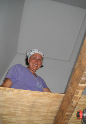 Woman in a purple shirt with white handkerchief headband working inside