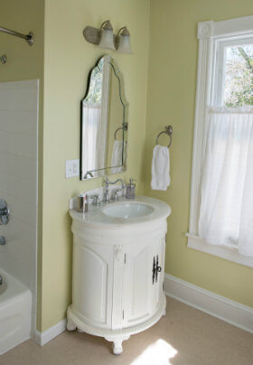 Light green bathroom with marble topped sink vanity beneath a hanging mirror